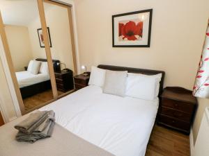 Un dormitorio con una cama blanca y un espejo. en Violet Lodge, en Saltburn-by-the-Sea