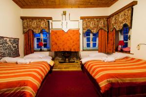two beds in a room with windows and red carpet at Archontiko 1787 in Tsepelovo