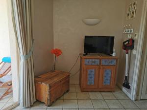 a living room with a television and a wooden cabinet at la baie des voiles ,vue lac d'Annecy ,plage privée in Duingt