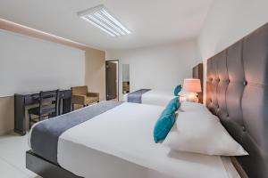 a bedroom with two beds and a desk at Ayenda Suites Ejecutivas Monterrey in Monterrey