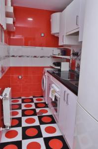 cocina roja y blanca con suelo blanco y negro en Departamentos C&G, en Madrid
