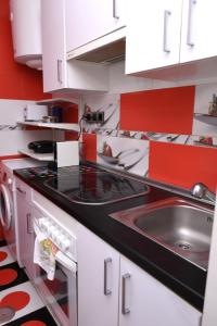 una cocina con armarios rojos y blancos y fregadero en Departamentos C&G, en Madrid