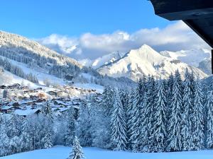 a snow covered mountain range with a village and trees at Luxury Family Ski Chalet - Jacuzzi BBQ - Near Lake Golf - Multipass access 60 Summer activities - Sleep 10 in Les Gets