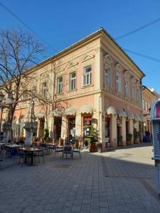 a large brick building with tables in front of it at Corso Rooms City Centre in Novi Sad