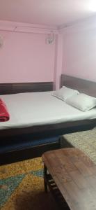 uma cama grande num quarto com uma mesa em Northeastern Dormitory em Gauripur