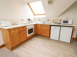 una cocina con armarios de madera y electrodomésticos blancos en Stewart, en Pitlochry