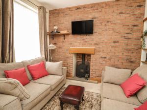 a living room with two couches and a brick wall at The Oaks Cottage in Penrith