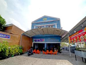a building with orange tables and chairs in front of it at OYO 90922 Gurusinga Guesthouse in Medan