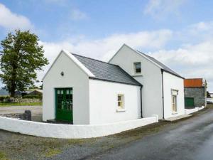 a white house with a green door on a street at Annie's Cottage in Clogher
