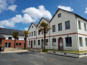 un grande edificio bianco con palme in un parcheggio di Auberge de Jeunesse HI Cherbourg a Cherbourg en Cotentin