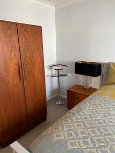 um quarto com um grande armário de madeira e uma televisão em Atlantic apartment em Sidmouth