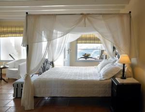 a bedroom with a canopy bed and a chair at Suites of the Gods Cave Spa Hotel in Megalochori