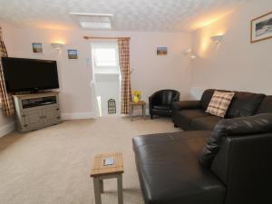 a living room with a black leather couch and a flat screen tv at Wingstone Farm Cottage in Newton Abbot