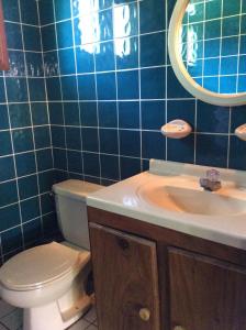 a blue tiled bathroom with a toilet and a sink at Villas de la Bahia Playa Tambor in Tambor