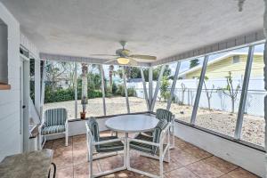 une véranda avec une moustiquaire, une table et des chaises ainsi qu'un ventilateur de plafond dans l'établissement Charming Ormond Beach Home - Walk to Beach!, à Ormond Beach