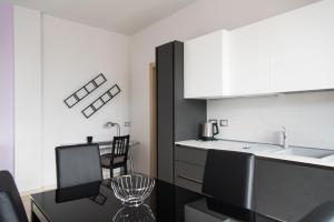 eine Küche mit weißen Schränken sowie einem Tisch und Stühlen in der Unterkunft YouHosty - Inganni 74 in Mailand