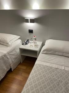 una camera d'albergo con due letti e un comodino tra di loro di Albergo Ligabue a Guastalla