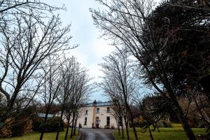 a house in the middle of a road with trees at Clone House Event Villa in Aughrim
