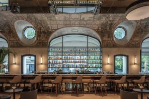 - un bar avec des tables et des chaises dans une pièce dotée de fenêtres dans l'établissement Hotel Lutetia, à Paris