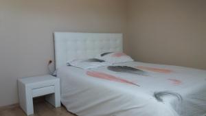 a bedroom with a white bed with pink feathers on it at Colocation ggayfriendly chez l'habitant près de la plage naturiste de Granville in Bréville-sur-Mer