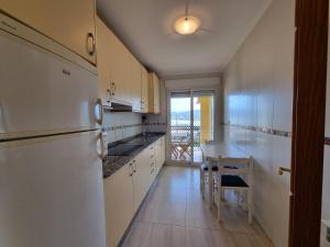 a kitchen with a white refrigerator and a table at Apartamentos Rapadoira in Foz