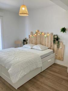 a bedroom with a white bed with a wooden headboard at Au cœur de Lacanau Océan Appartement neuf avec parking in Lacanau-Océan