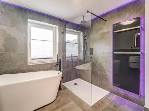 La salle de bains est pourvue d'une baignoire blanche et d'un éclairage violet. dans l'établissement High quality apartment with whirlpool, à Dorf