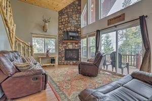 a living room with leather furniture and a stone fireplace at Serene Pet-Friendly Cabin with Fire Pit and Loft! in Duck Creek Village