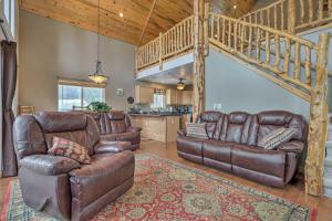 a living room with leather furniture and a staircase at Serene Pet-Friendly Cabin with Fire Pit and Loft! in Duck Creek Village