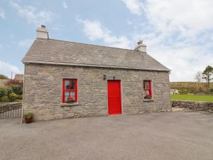 um pequeno edifício de pedra com uma porta vermelha em Limestone Cottage em Ennis