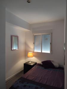 a bedroom with a bed and a lamp and two windows at Avenue Rooms in Valencia