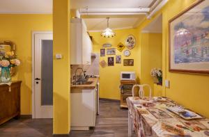 a kitchen with yellow walls and a table and a sink at Annina's House Varenna Historic Centre in Varenna