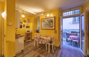 cocina y comedor con paredes amarillas, mesa y sillas en Annina's House Varenna Historic Centre, en Varenna