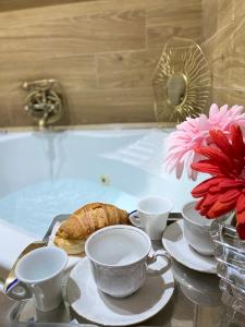 een tafel met theekopjes en een croissant in een bad bij Suite room in Aversa