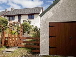 una casa con una puerta de madera y una valla en Taigh Na Talia - 2 Sandholm, en Mallaig
