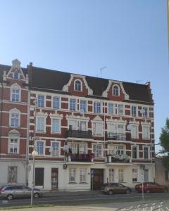 un gran edificio de ladrillo con coches estacionados frente a él en Apartament przy galerii FORUM Gliwice Witkiewicza, en Gliwice