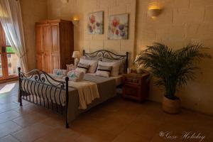 a bedroom with a bed with pillows and a plant at Lellux Qala in Qala