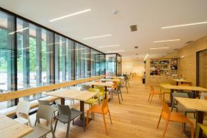 a cafeteria with tables and chairs and windows at Vallesinella Hotel Restaurant Bar in Madonna di Campiglio