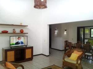 ein Wohnzimmer mit Flachbildfernseher und Stühlen in der Unterkunft Chalé Luxo Frente Piscina - Praia da Pipa in Pipa