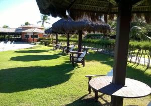 eine Gruppe von Tischen und Stühlen mit Sonnenschirmen in der Unterkunft Chalé Luxo Frente Piscina - Praia da Pipa in Pipa
