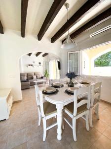 un comedor blanco con una mesa y sillas blancas en Chalet Villafranca Menorca con piscina privada, en Cala'n Bosch