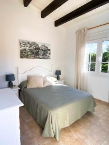 1 dormitorio con 1 cama y 2 ventanas en Chalet Villafranca Menorca con piscina privada, en Cala'n Bosch