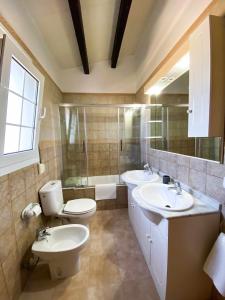 ein Badezimmer mit zwei Waschbecken, einer Toilette und einer Badewanne in der Unterkunft Chalet Villafranca Menorca con piscina privada in Cala'n Bosch