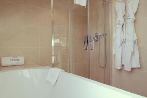 a bathroom with a shower with white towels and a tub at Hôtel de Sèze & Spa Bordeaux Centre in Bordeaux