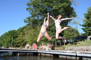 two girls jumping off a dock into the water at The Lodges at Sunset Village in McHenry