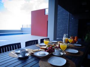 a table with plates of food and glasses of orange juice at Mar & Serra in Feteiras