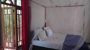 a bedroom with a white canopy bed with a window at Isurindi Villa in Midigama East