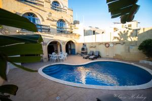 a swimming pool in front of a building at Lellux Qala in Qala