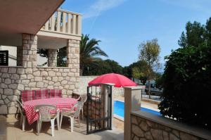 a table and chairs with a red umbrella on a patio at Holiday Apartement Marija Supetar with private pool in Supetar