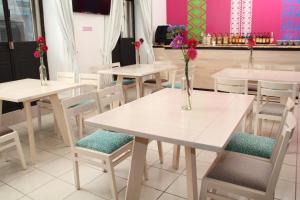 a restaurant with white tables and chairs and pink walls at Hotel La Casa de María in Oaxaca City